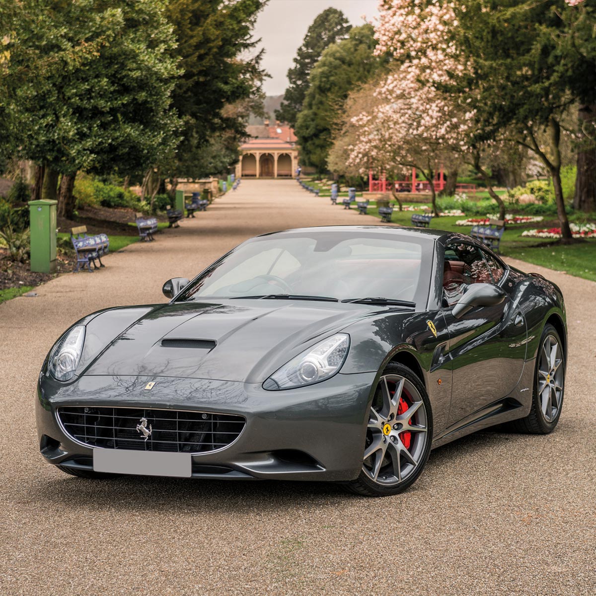 A Ferrari California parked in a beautiful park.