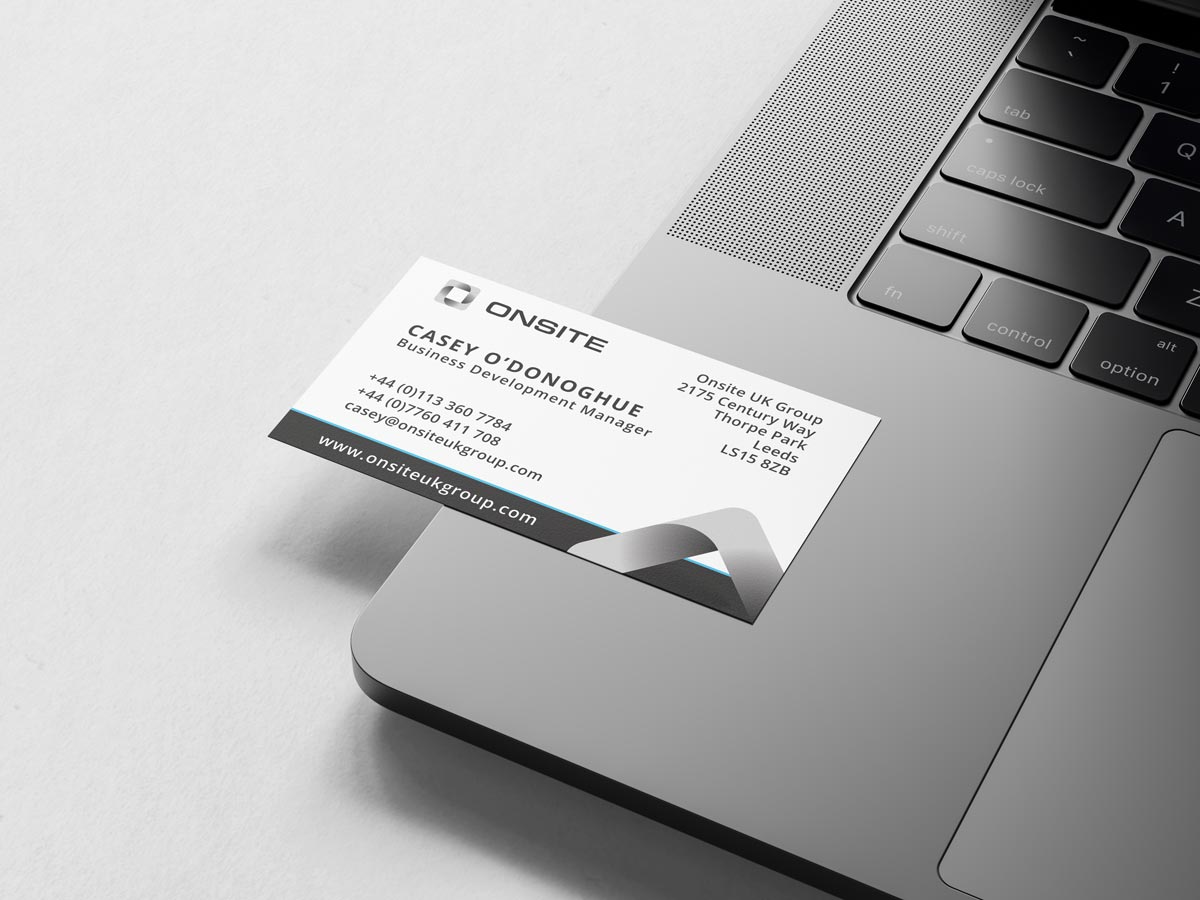 Business card showing Onsite UK Group details while resting on top of a laptop