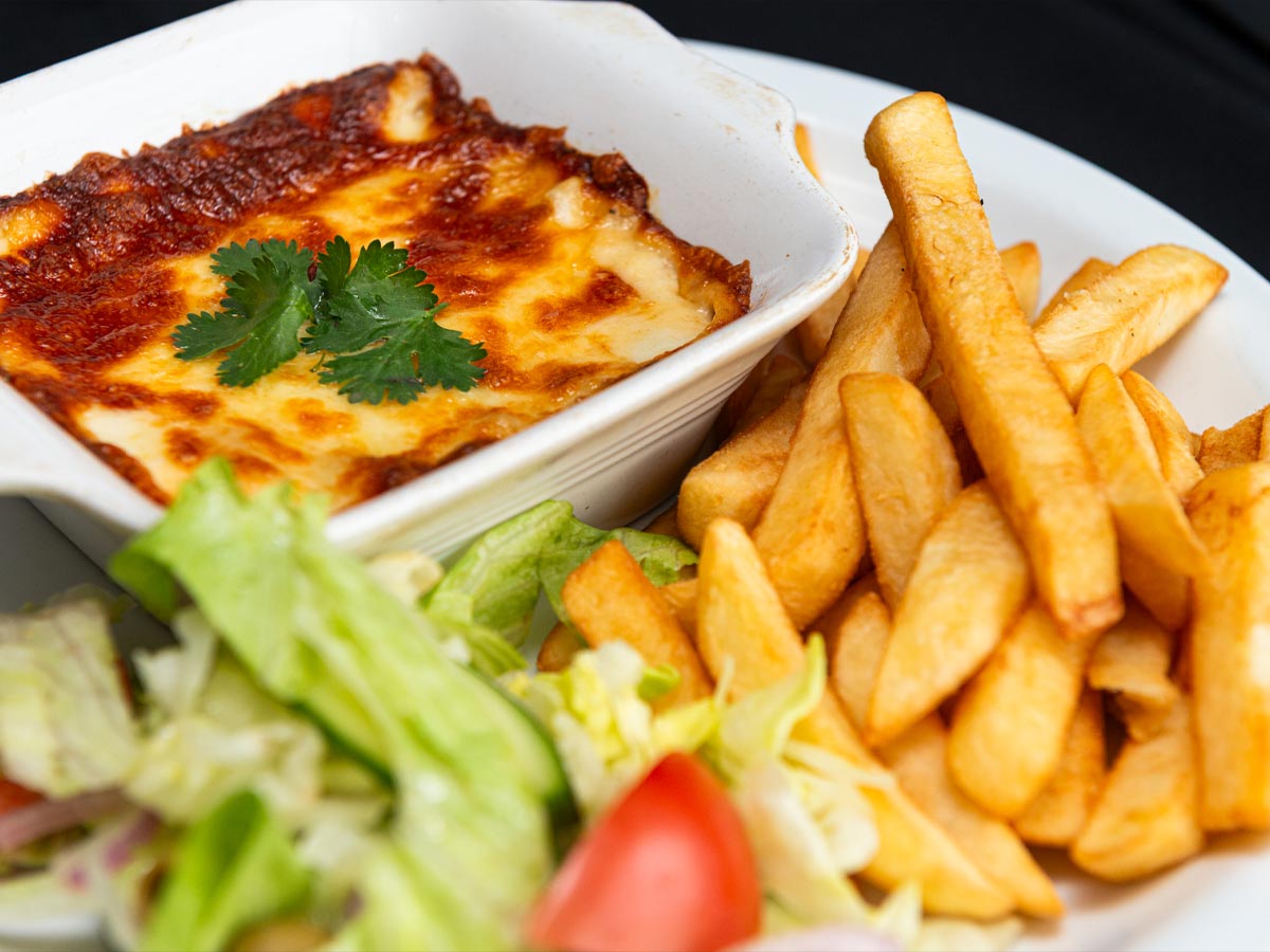 Close up of lasagne and chips with salad on a plate